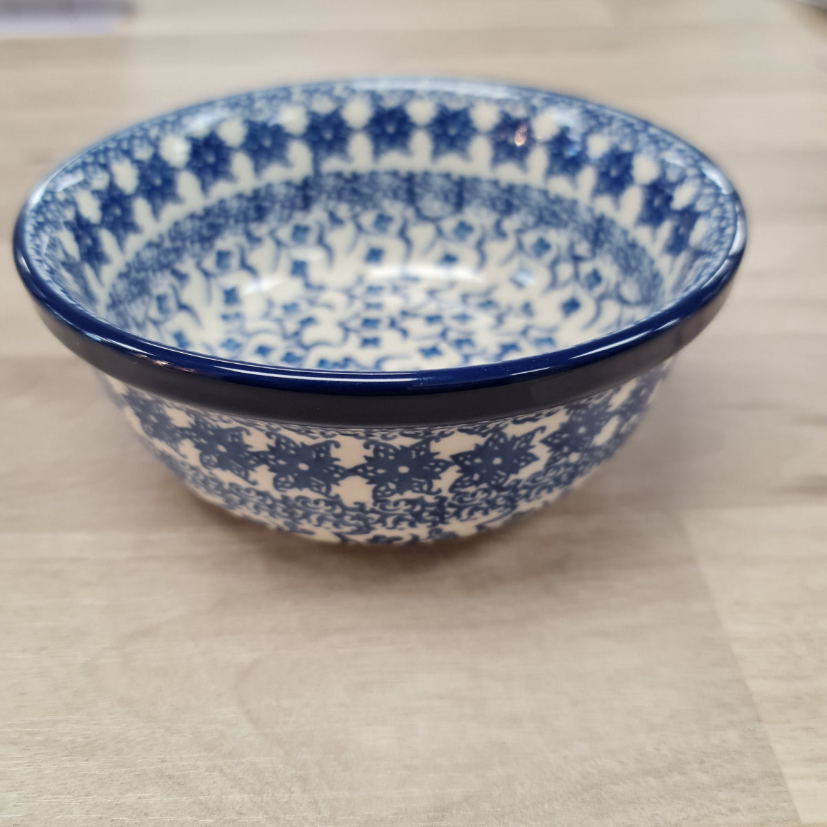 Ceramic bowl with blue and white pattern on a beige surface