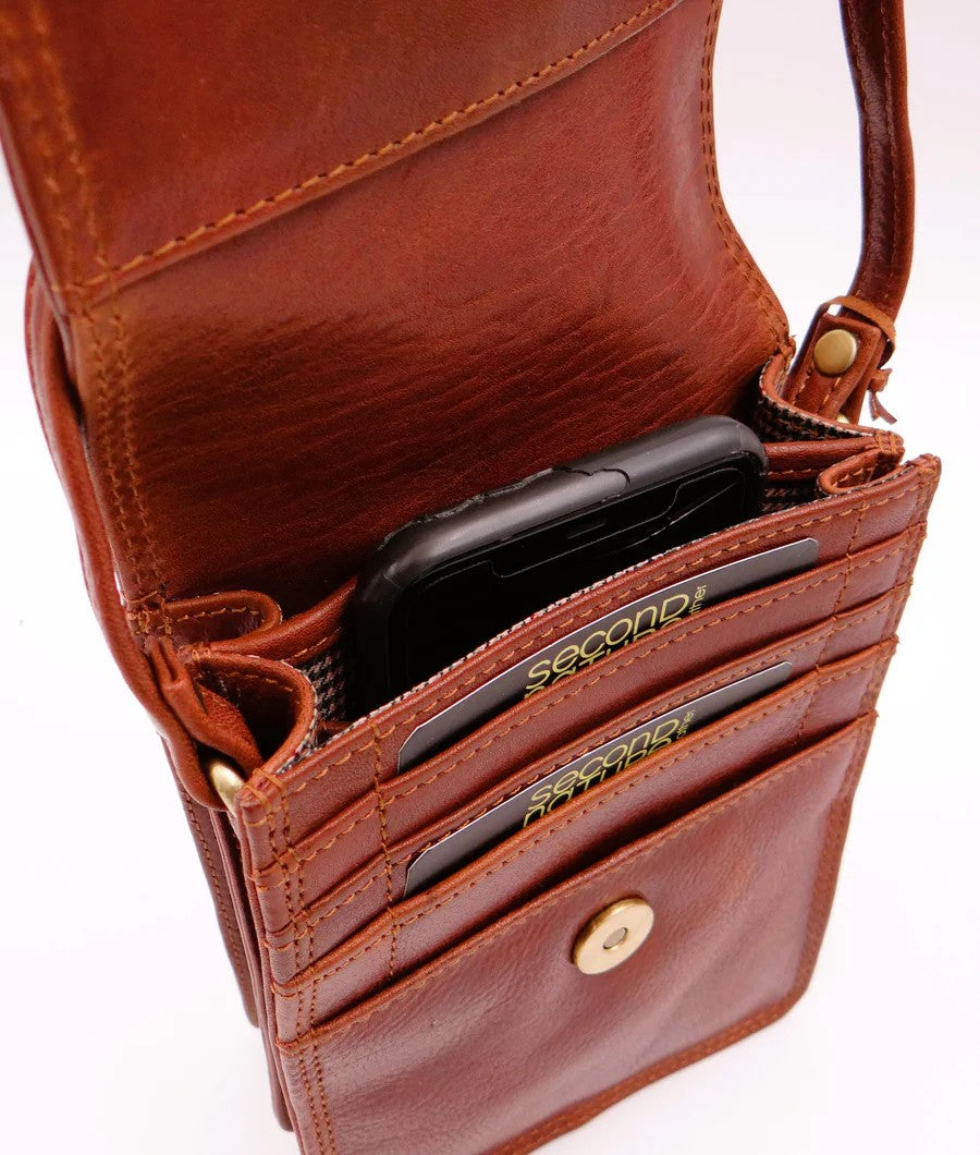 Brown leather wallet with card slots and a phone inside on a white background