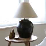 CC Interiors Romo Lampbase shown here with the Biscotti 51cm lamp shade at Cerise. The shade is sold seperately. Handmade from hand beaten aluminium and finished in an antique bronze colour. Shown here on a light wood side  table.