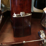Stainless Steel Hip Flask wrapped in a dark brown leather cover with beautiful topstitching. Shown on a leather tray, beautiful quality and great Gift idea  for a man for 21st Birthday, graduation, retirement or any milestone celebration at Cerise