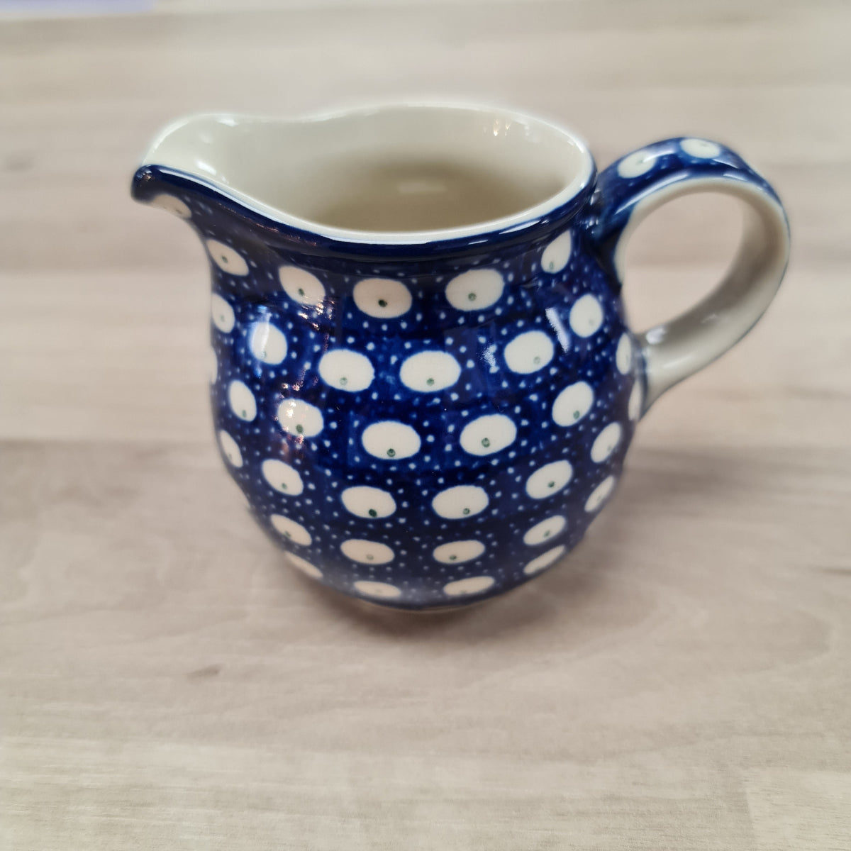 Blue pottery jug  with white  dots on a beige background
