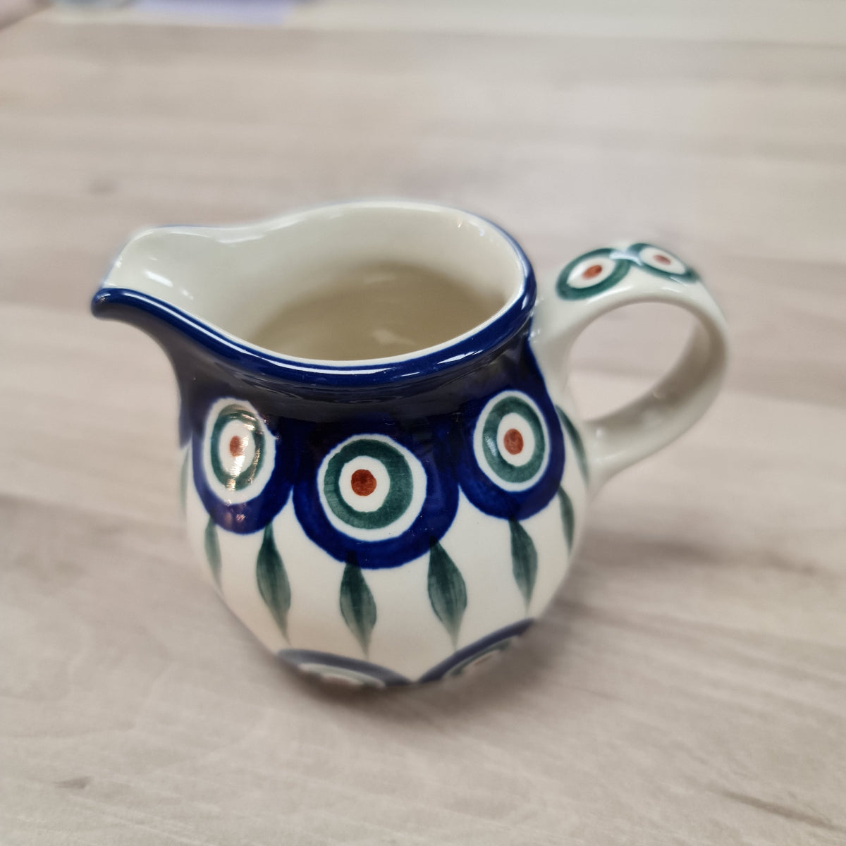 pottery small ceramic jug in blue, craam, green and bown peacock pattern