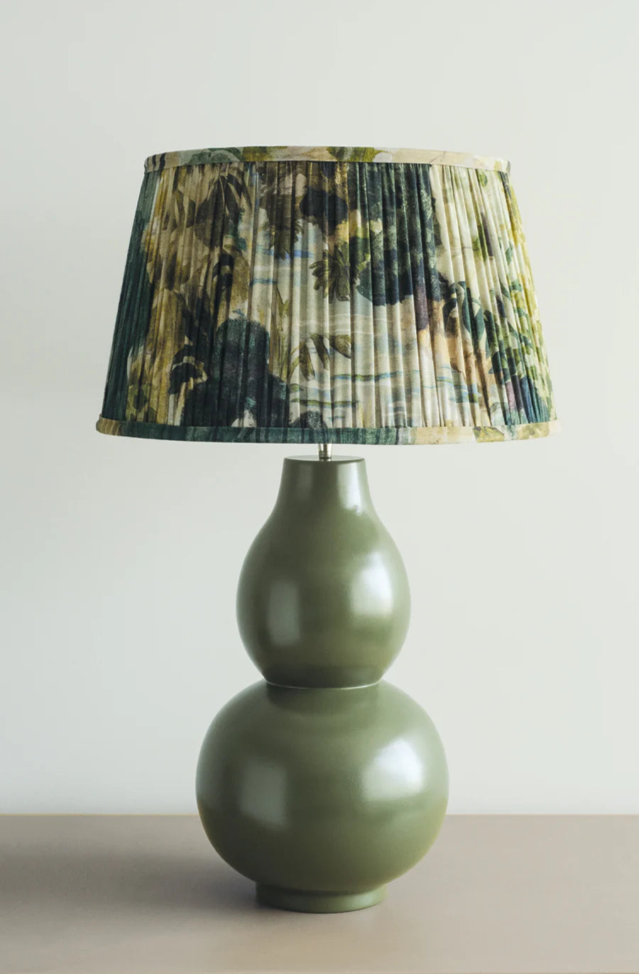 Green curved bulb shape lamp with pleated floral green shade.