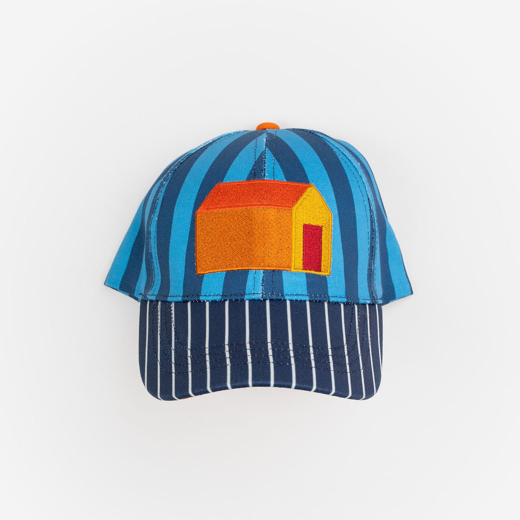 Das Ist Maurice Cap in House design at Cerise. Featuring bold blue and navy stripes, this fun children’s cap is finished with a bright house appliqué on the front for a cheerful, imaginative touch.