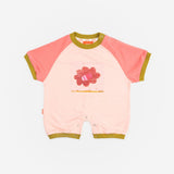 Das Ist Maurice Romper in Pink Petal at Cerise. A sweet, hand-drawn “Pink Petal” artwork sits across the chest, adding a unique and playful touch. Contrasting bright coral raglan sleeves bring a vibrant pop of colour, while olive green ribbed trims.