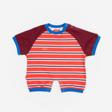 Das Ist Maurice Romper in sunset design featuring bright red and blue striped body with contrast burgundy sleeves bound in a bright blue.  A sporty look for babies and toddlers at Cerise.