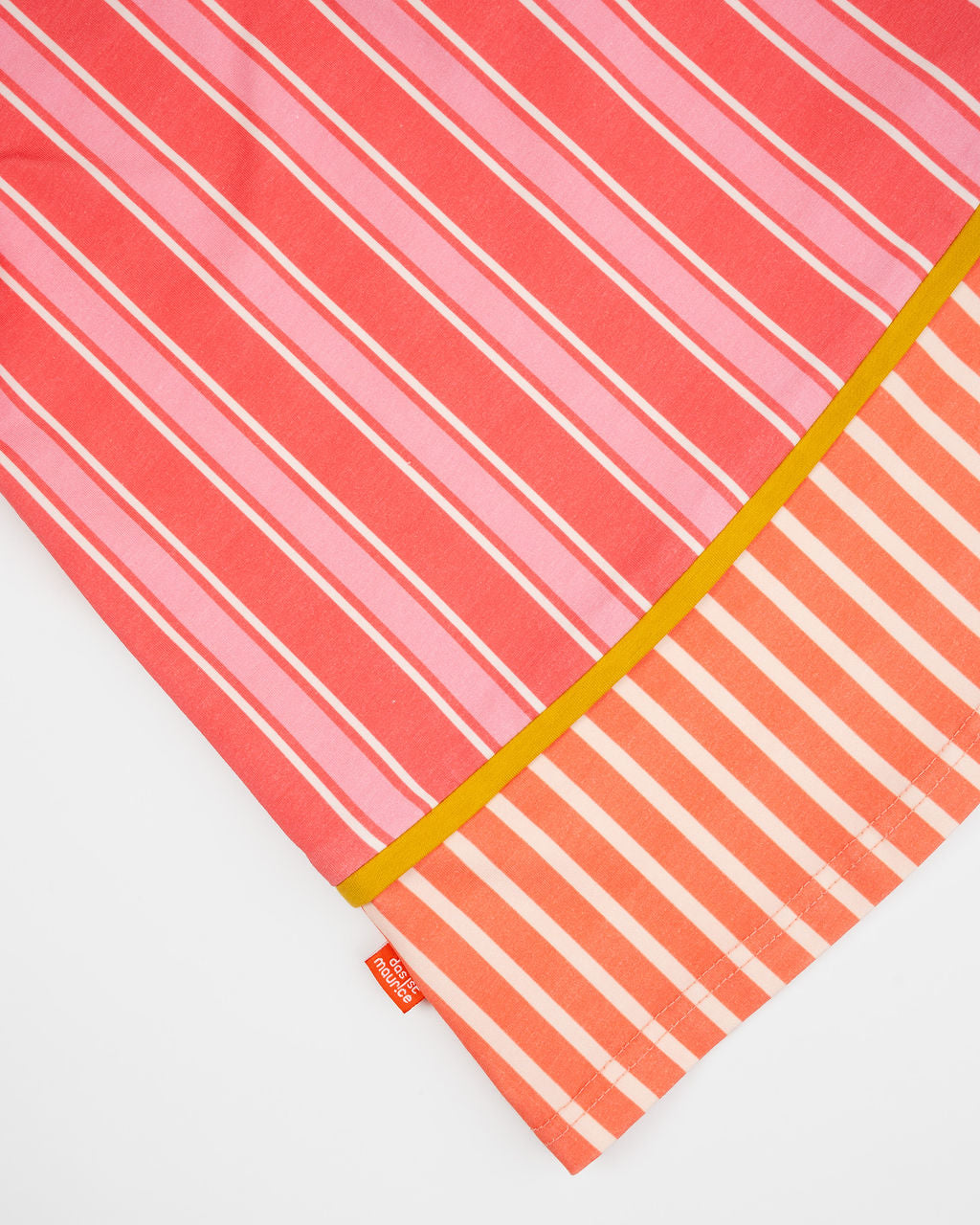 Das Ist Maruice Sleeveless Dress in Coral at Cerise. The relaxed A-line silhouette provides plenty of room for movement, making this sleeveless kids’ dress ideal for active days. Featuring bold coral and peach stripes, the dress has a fun retro-inspired look with a vibrant mustard yellow neckline and contrasting trim