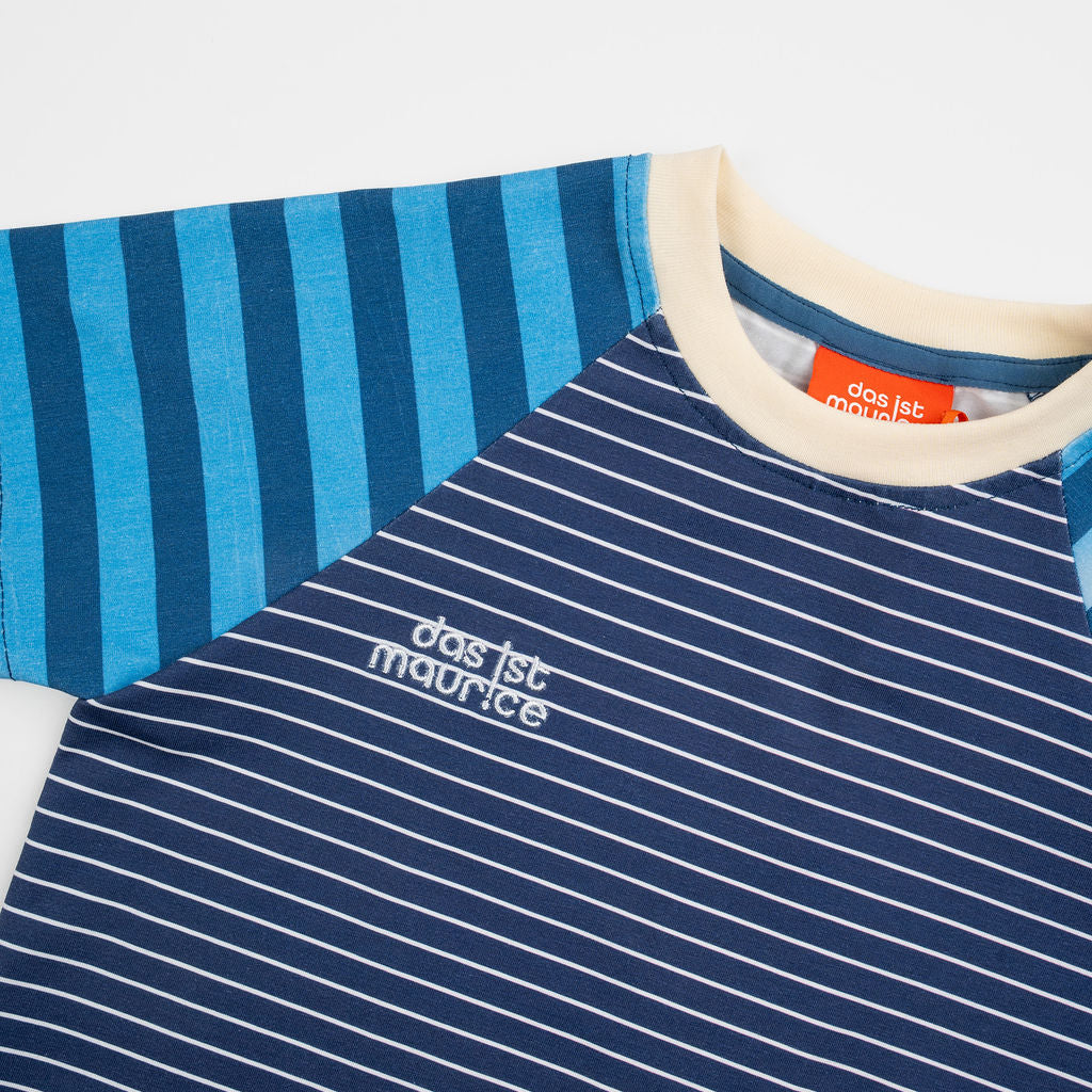 Das Ist Maurice Tshirtin Seabreeze Stripe at Cerise.  Contrasting blue and navy vertical stripes on the raglan sleeves create a fun mix of patterns and colour, giving this striped kids’ T-shirt a distinctive Das Ist Maurice finish. The combination of classic stripes and playful colour blocking makes it an easy piece to style with kids’ shorts, pants or jeans.