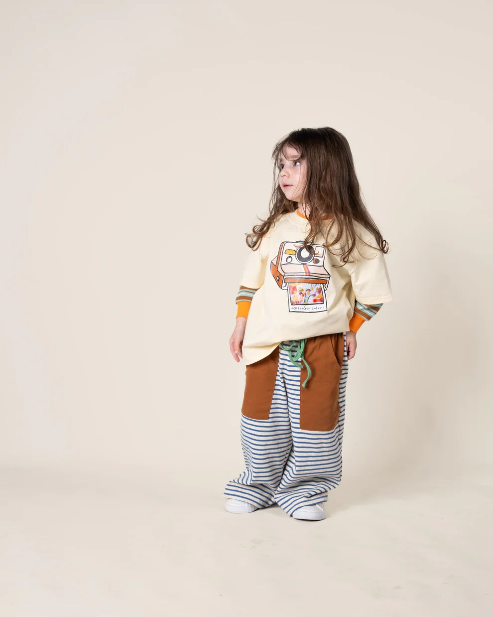 Das Ist Maurice off white coloured  retro illustrated polaroid t-shirt with a nostalgic photo print on the front featuring our September Safari hand painted abstract artwork. Pictured here with our Das Ist Maurice wide stripe pant at Cerise NZ.