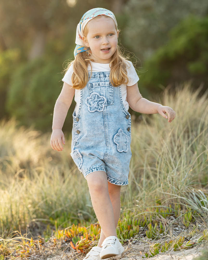 Light blue denim overalls with frayed edge decorative floral patches