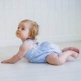 Baby wearing a blue striped romper sitting on a white surface.
