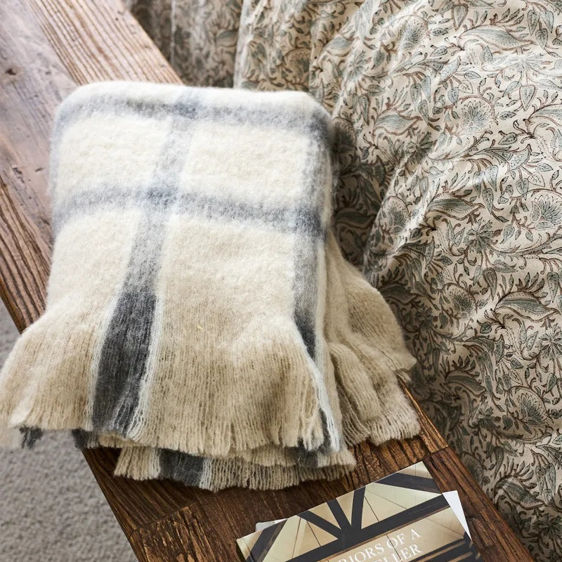 Juniper Throw from French Country Collections at Cerise. Featuring Grey Check stripes on a neutral background. with tassles.  Great for the sofa, end of bed or simply to snuggle up in.