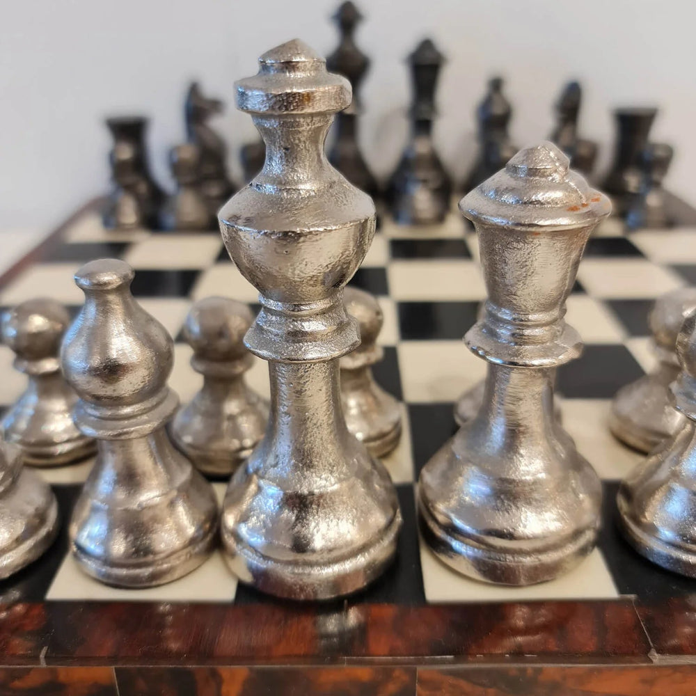Close up picture of the French Country Chess set at Cerise showing the aluminium chess pieces on a wooden board with sesin inlay squares.