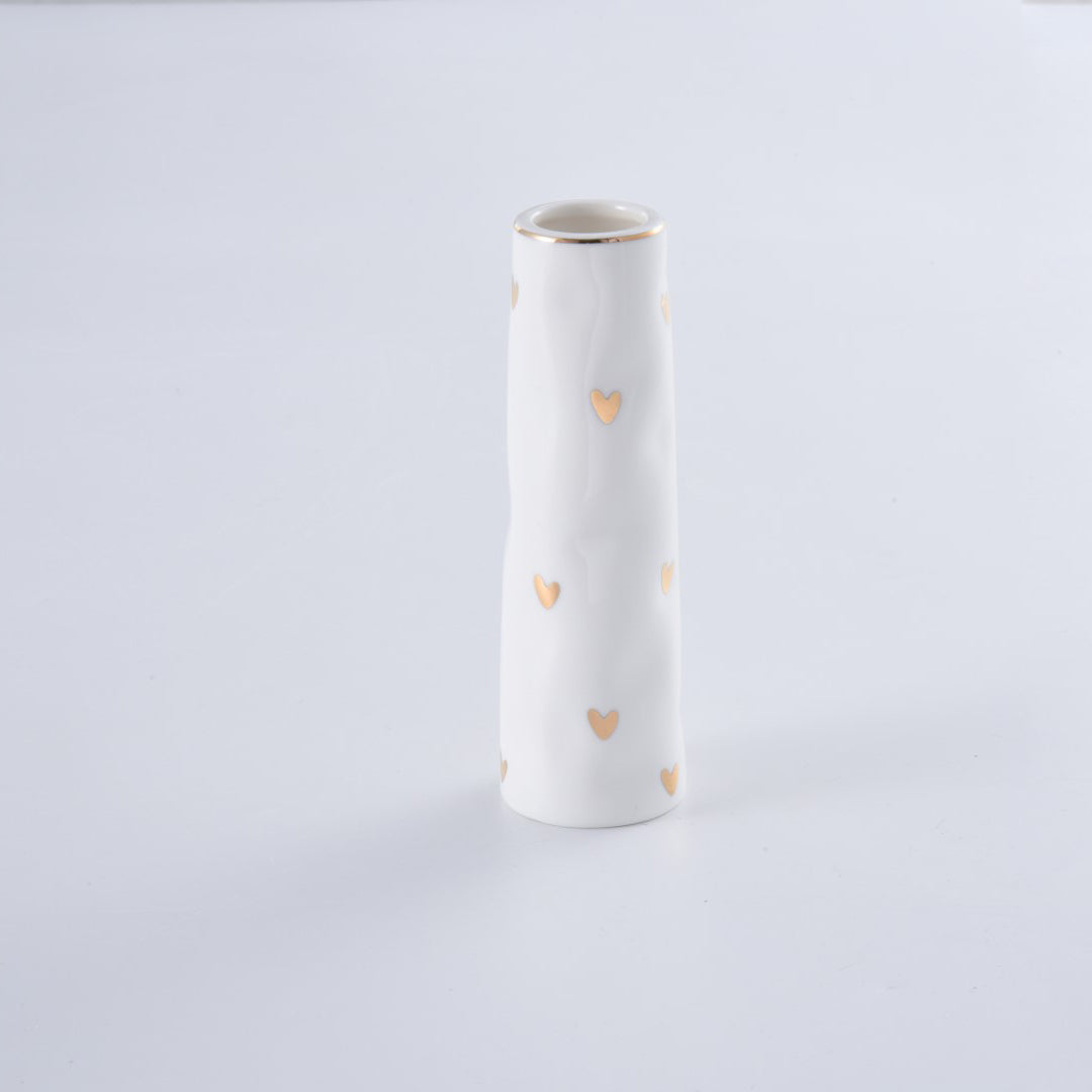 White vase with gold heart patterns on a light gray background