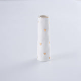 White vase with gold heart patterns on a light gray background