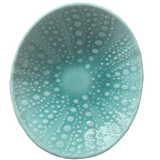 Teal ceramic bowl with white speckled pattern on a white background