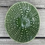 Green ceramic plate with bubble texture on a wooden surface