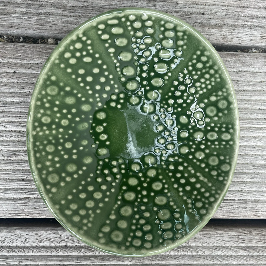 Green ceramic plate with bubble texture on a wooden surface