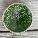Green kina ceramic bowl with bubble pattern on a wooden background