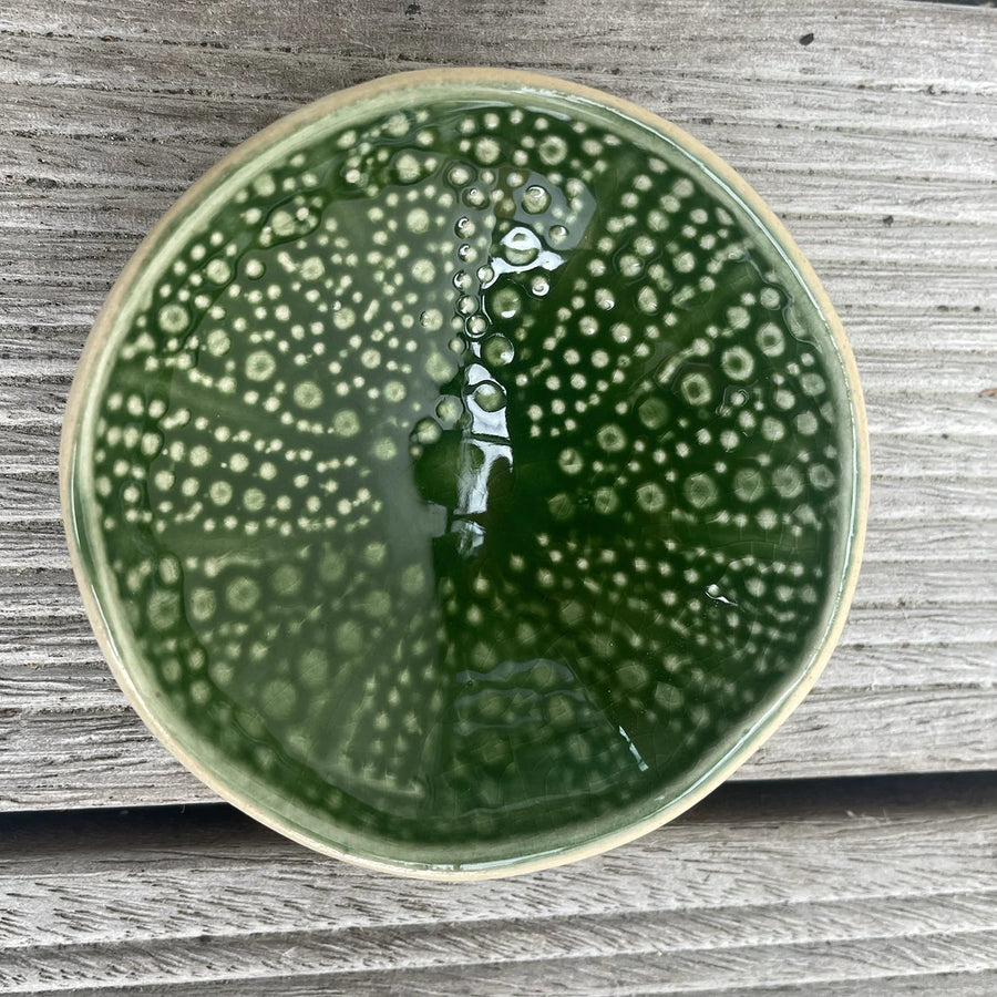 Green kina ceramic bowl with bubble pattern on a wooden background