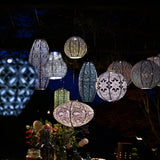 Group concept photo of hanging lumiz solar lanterns at dusk. Showing intricate design patterns and colours as they glow in the evening.