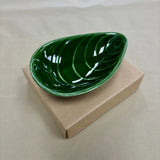 Green mussel shaped bowl on cardboard box.