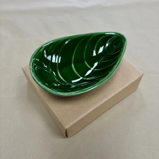 Green mussel shaped bowl on cardboard box.