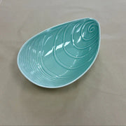 Aqua mussel shaped ceramic bowl on a plain background