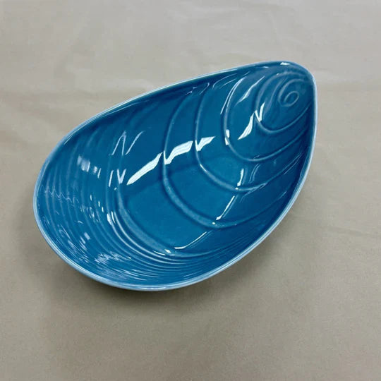Blue mussel shaped ceramic bowl on a plain background