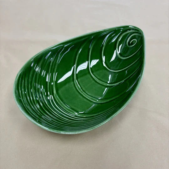 Green mussel shaped ceramic bowl on a plain background