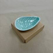 Aqua mussel shaped ceramic bowl on a plain background