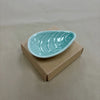 Aqua mussel shaped ceramic bowl on a plain background