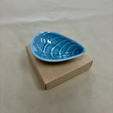 Blue mussel shaped ceramic bowl on a plain background
