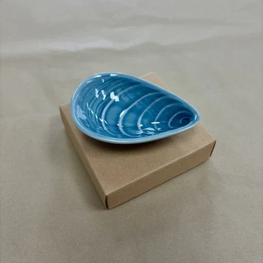 Blue mussel shaped ceramic bowl on a plain background