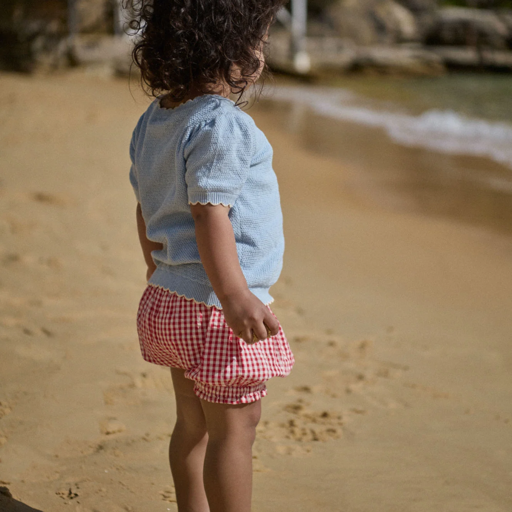 Nature Baby Betty shorts in Red Gingham print at Cerise.  Made with cotton poplin and feature cute frills around the legs and elastic waist.