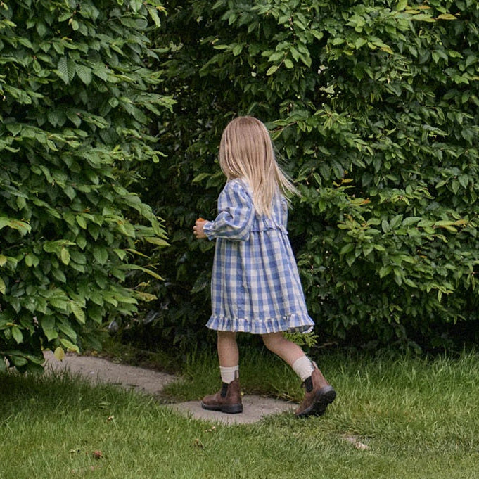 Little girl wearing bluebelle check Nora Dress by Nature Baby at Cerise