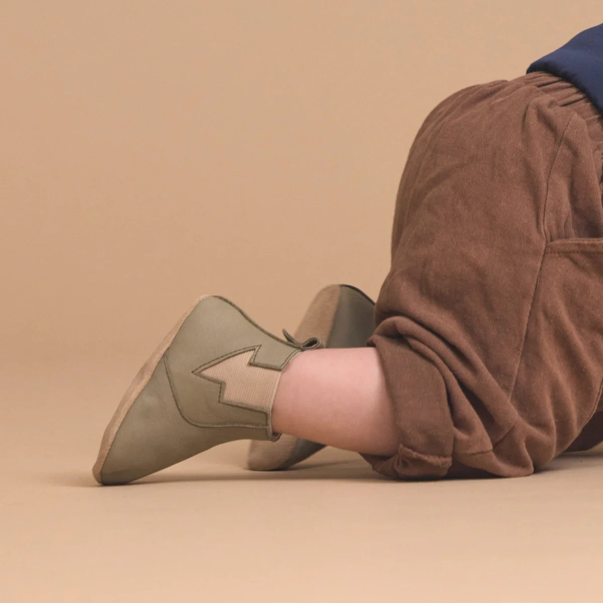 Concept photo of baby wearing Pretty Brave Electric Baby Shoe in olive colour at Cerise. Made from soft leather with suede lining and soft sole.