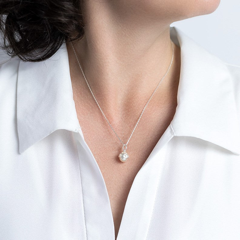 Model wearing a silver necklace with and pearl partly encased in silver engraved with hearts. Comes with a 45cm silver chain