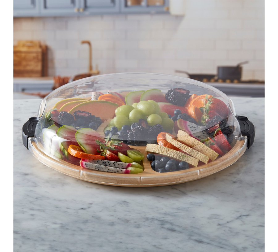 Fruit and vegetable platter with a dome cover on a marble countertop