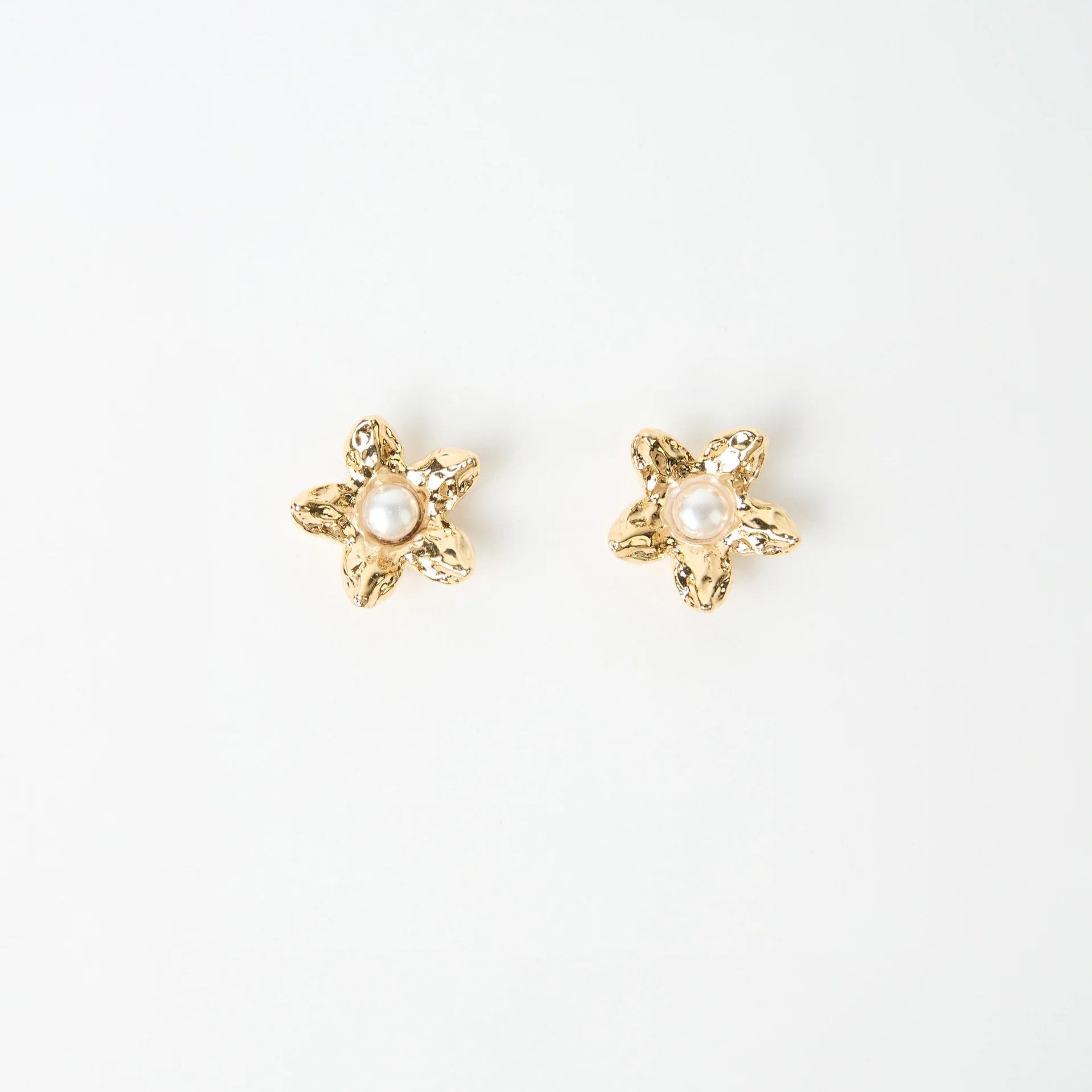 Gold flower shaped beaten earrings with pearl in the centre