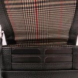 Close-up of a black leather bag showing card slots with plaid interior lining.