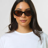 Woman wearing black sunglasses against a plain background