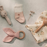 Over the Dandelions Set of 2 Baby Socks in soft pink and ivory with a cherry motif  design at Cerise. Made from soft organic cotton to fit newborn babies size 0 to 6 months. Shown here with Bunny Crochet Rattle and Daisy Bup cloths as a newborn baby gift idea.