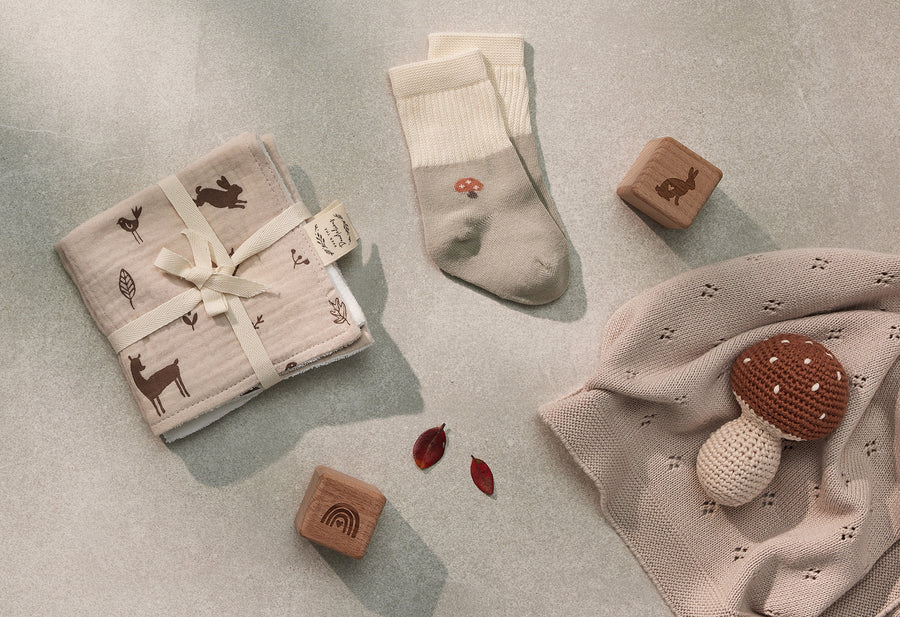 Over the Dandelions Set of 2 Baby Socks in sage green and ivoryMushroom design at Cerise. Made from soft organic cotton to fit newborn babies size 0 to 6 months. Shown with Woodland Wash Cloths for a newborn baby gift idea.