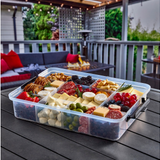 Transparent food storage container with assorted snacks on a wooden deck