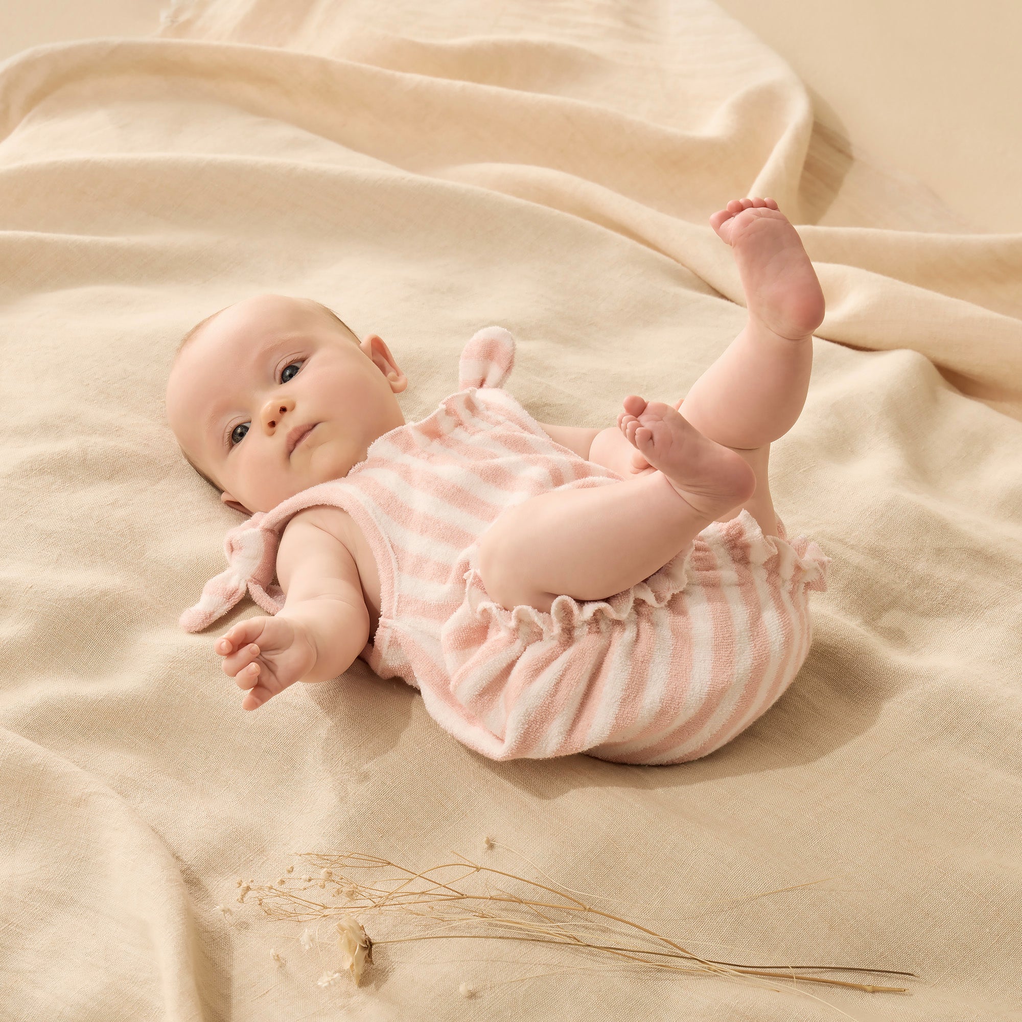 Baby wearing Soft strawberry colour and white stripes playsuit with tie straps and shirred legs