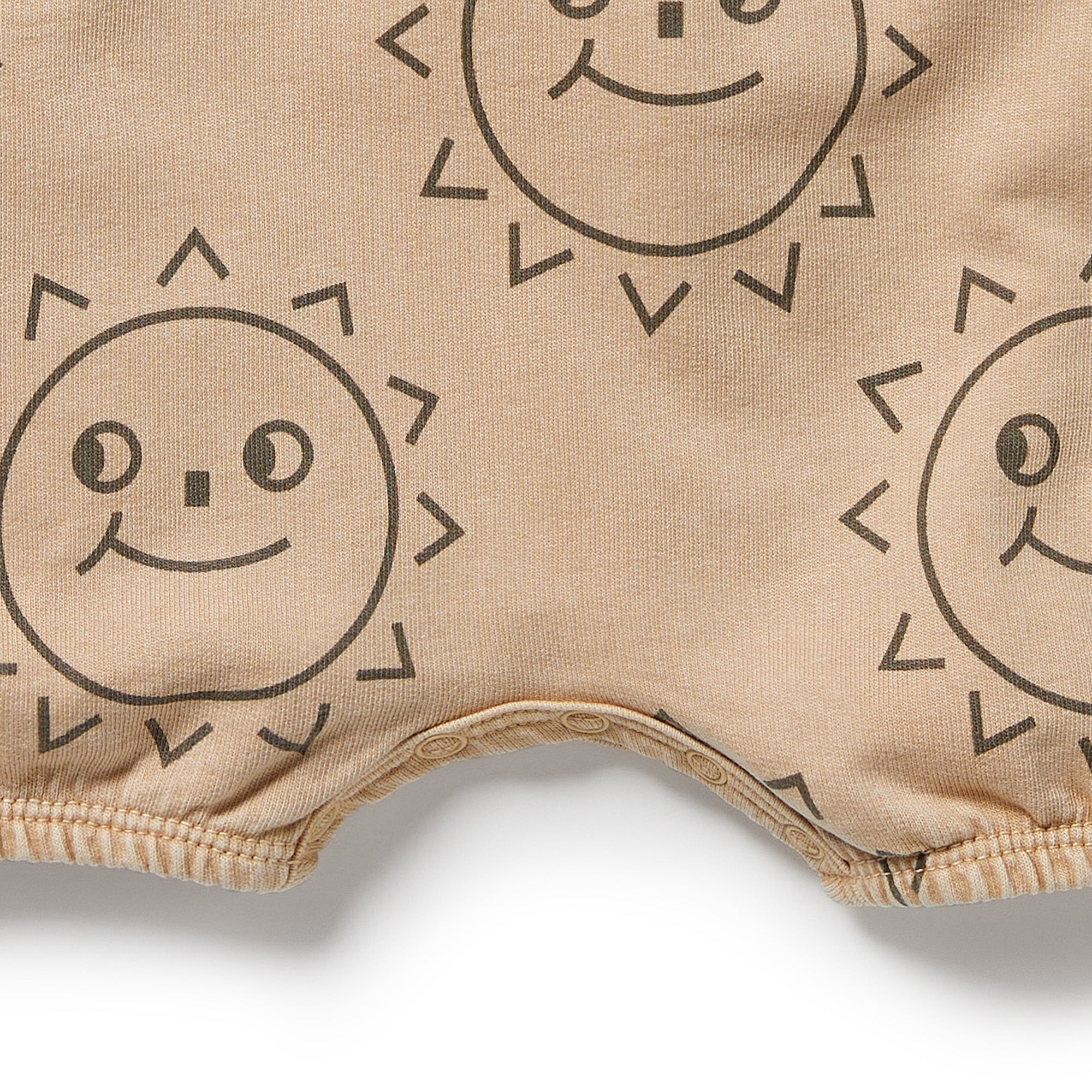 Baby grow suit in caramel colour with brown sun faces. dome crotch and short sleeves with front feature pocket - close up view of pattern