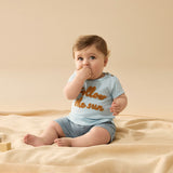 Baby wearing light blue tee shirt with follow the sun embroidered logo on front