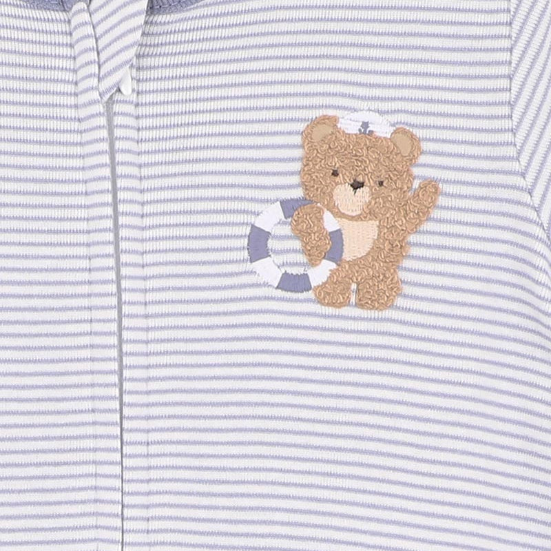 Close-up of a baby outfit with a teddy bear design on a striped background