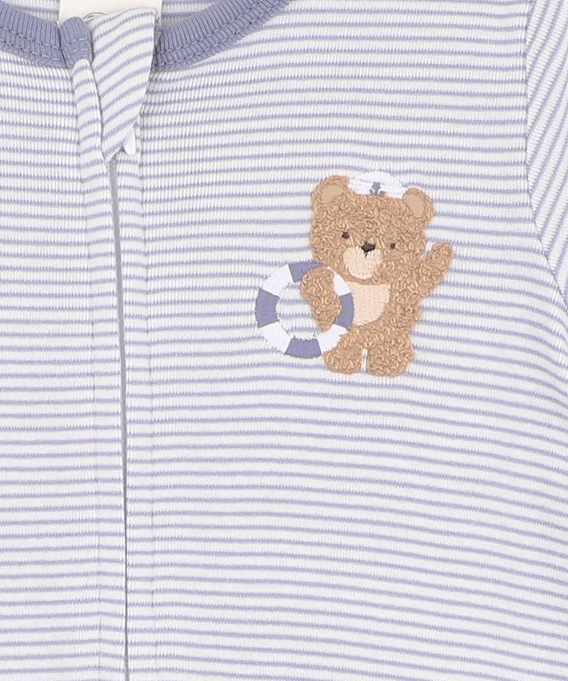 Close-up of a baby outfit with a teddy bear design on a striped background